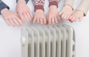 Family warming up hands over electric heater